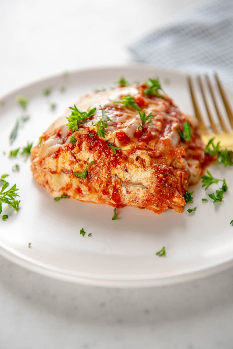 side view of cheesy lasagna layers on white plate