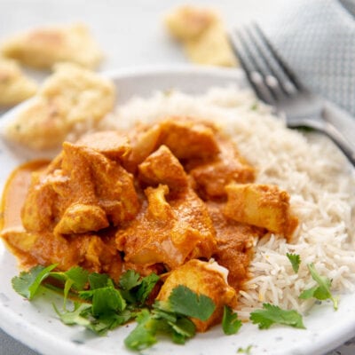 butter chicken with rice on a white plate