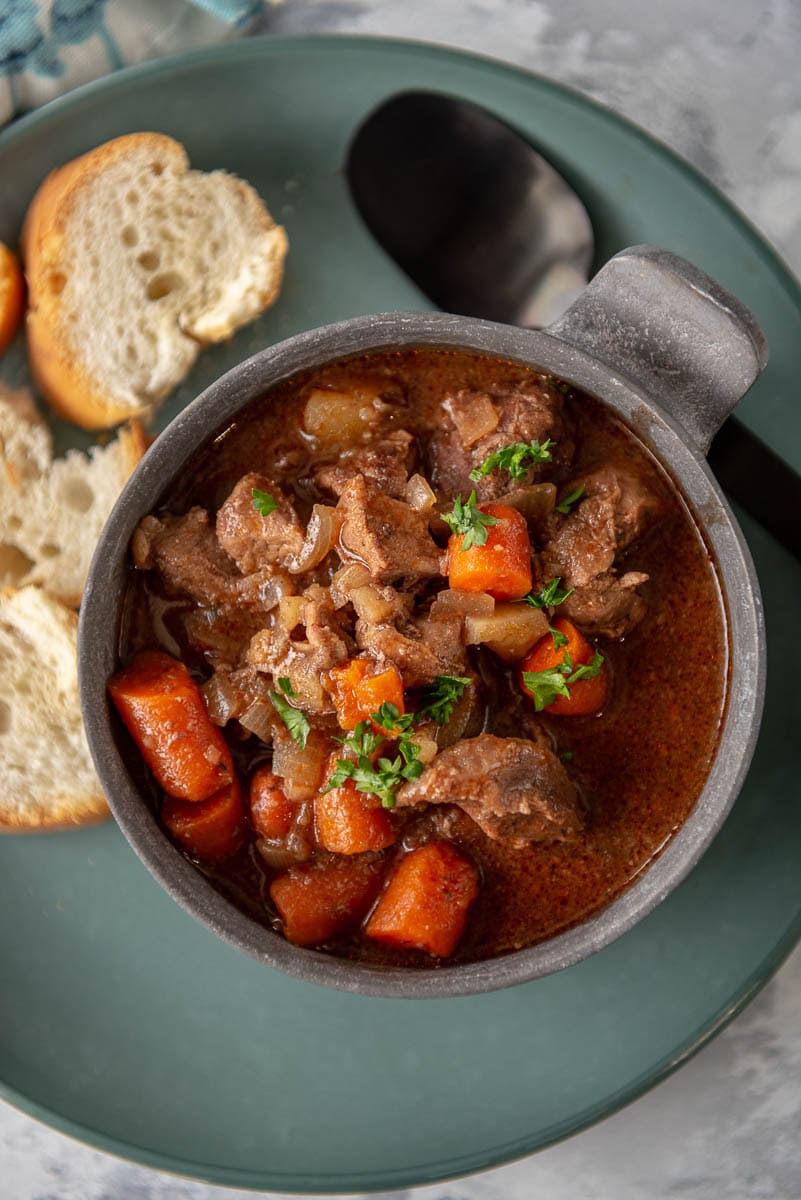 bowl filled with beef stew on a plate with crusty bread