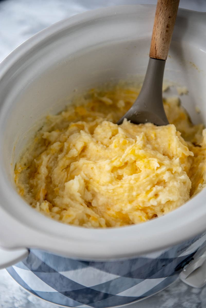 stirring mashed potatoes in slow cooker with spoon