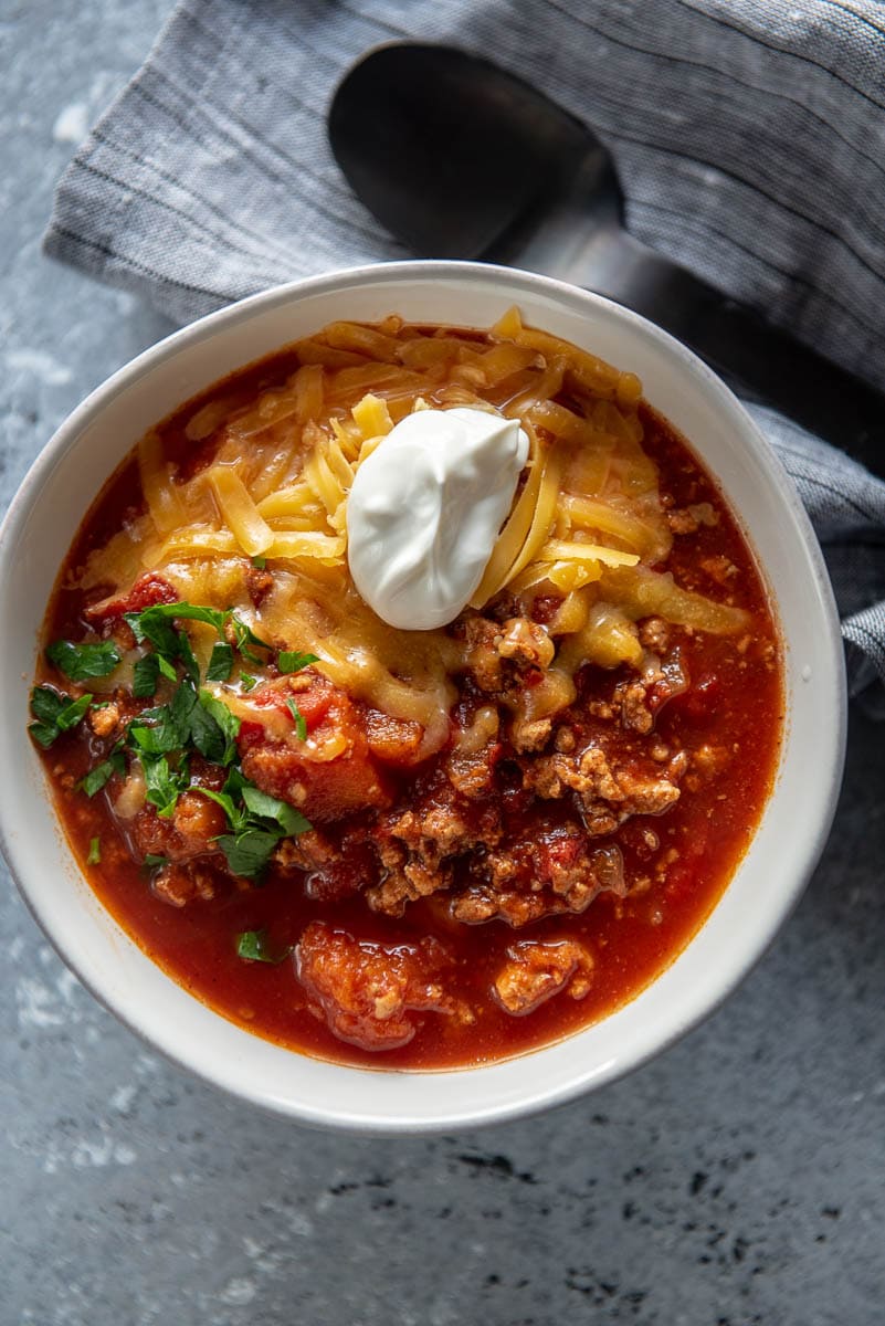 white bowl of turkey chili topped with sour cream
