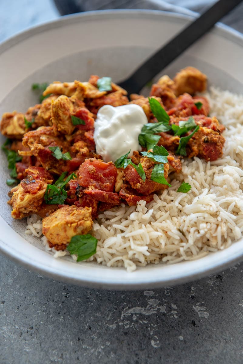 moroccan chicken in gray bowl on rice with sour cream