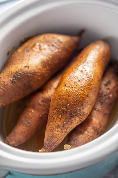 baked sweet potatoes in a white slow cooker
