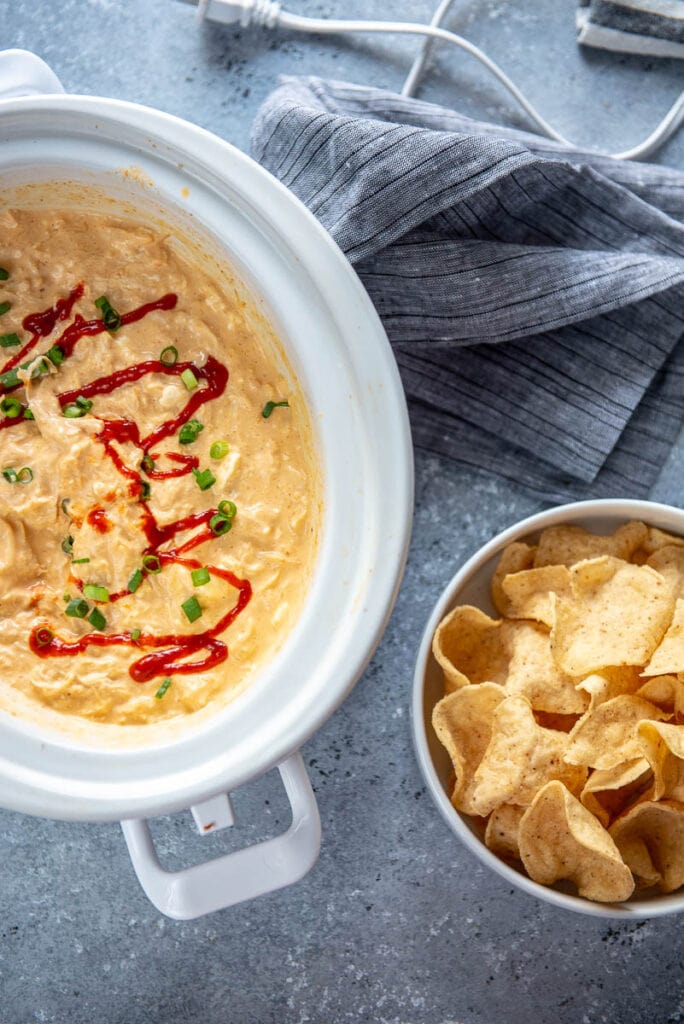 slow cooker with sriracha chicken dip and bowl of chips