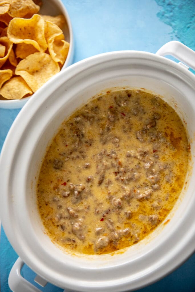 sausage cheese dip in slow cooker with bowl of chips