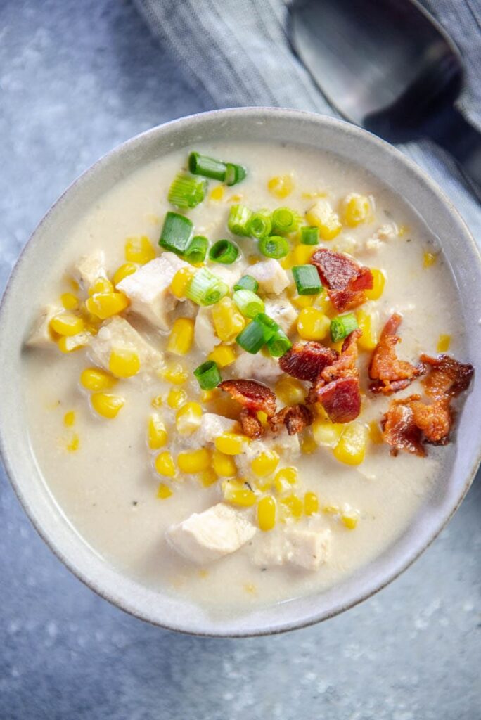 chicken corn chowder topped with bacon and chives in gray bowl