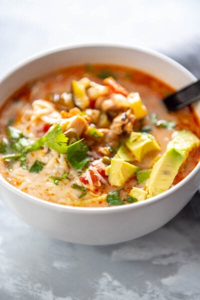 bowl of chicken taco soup topped with cilantro and avocado