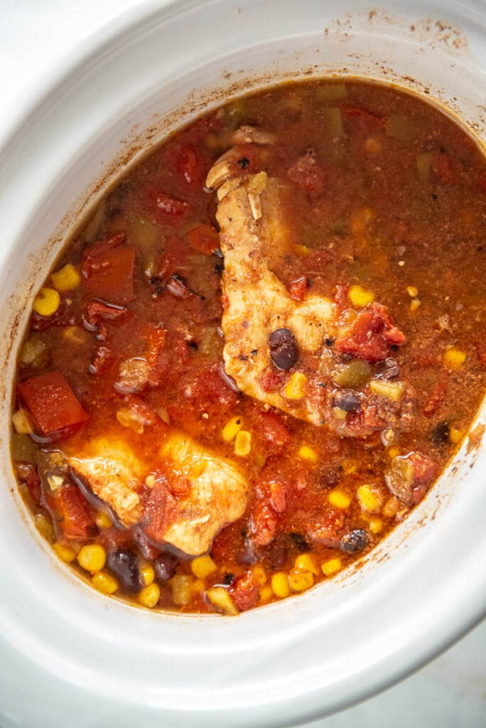 cooked mexican chicken with tomatoes in white slow cooker
