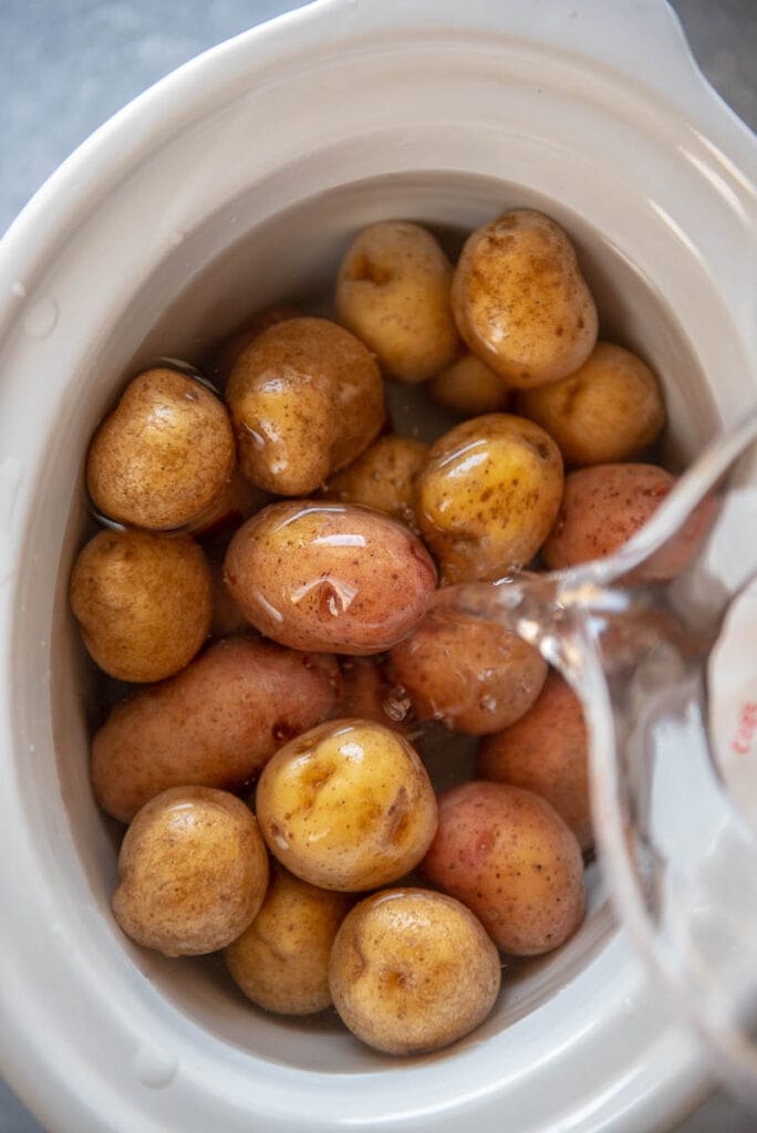 adding water to baby potatoes in slow cooker