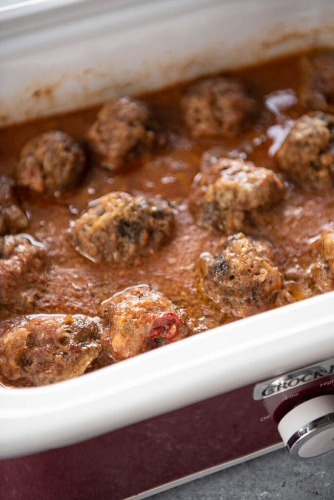 slow cooker of cooked gluten free meatballs with gravy sauce
