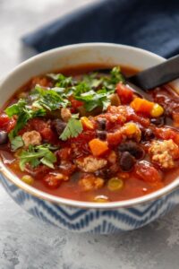 turkey soup with veggies in a white and blue bowl
