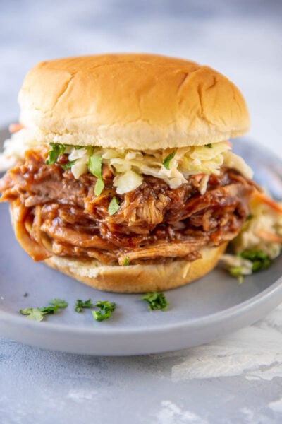 bbq pulled pork on bun topped with coleslaw on gray plate