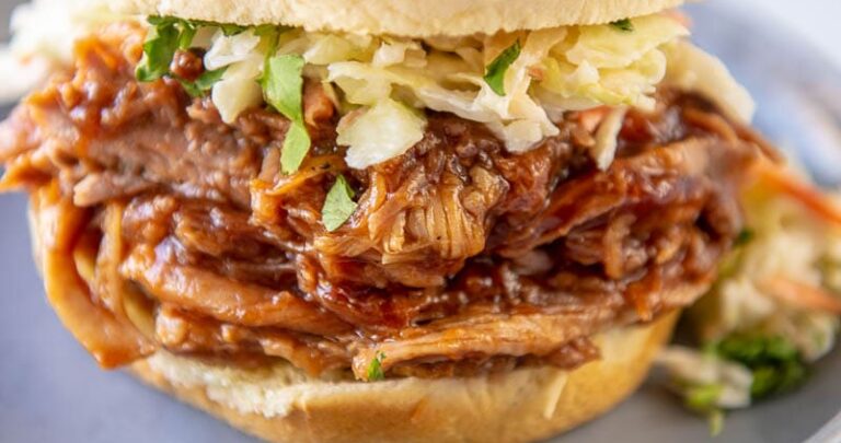 bbq pulled pork on bun topped with coleslaw on gray plate