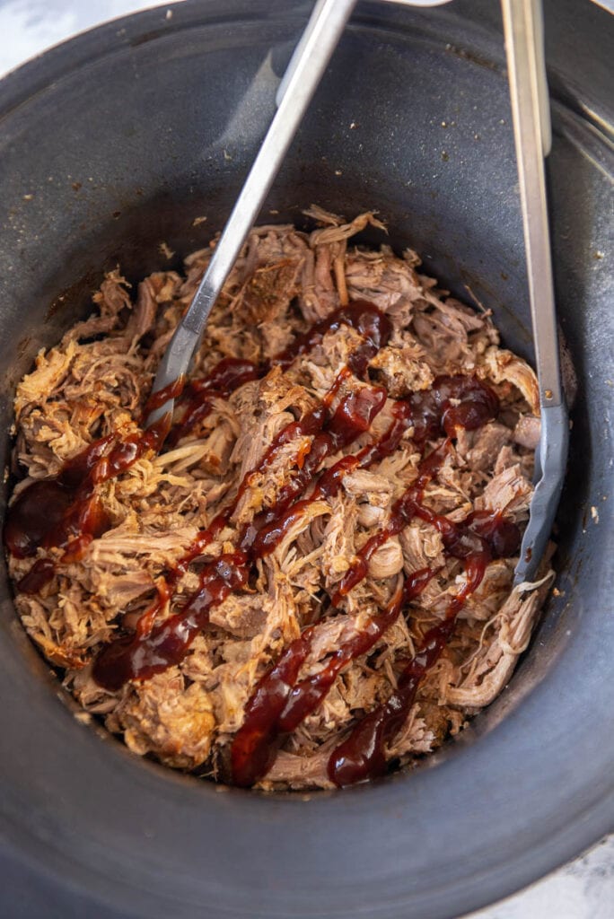 slow cooker with shredded pork and drizzle of bbq sauce