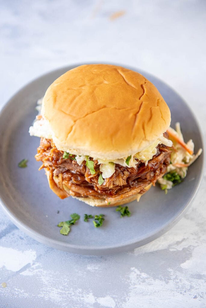 overhead view of bbq pork sandwich with coleslaw on a gray plate