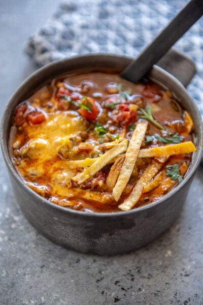 chili in a metal bowl topped with tortilla strips