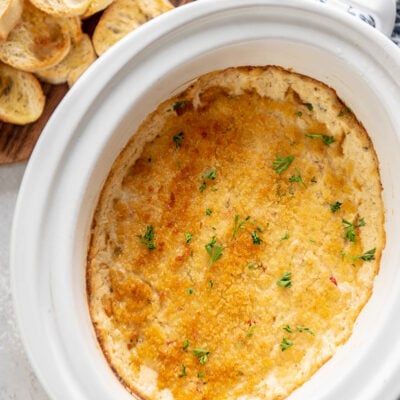 slow cooker filled with toasted crab dip with a side of bread
