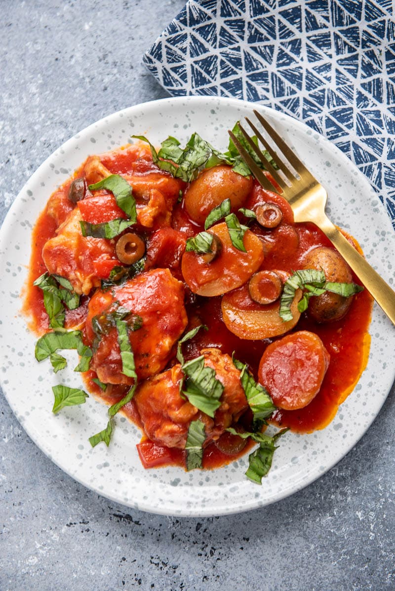 chicken cacciatore on a white plate with fork