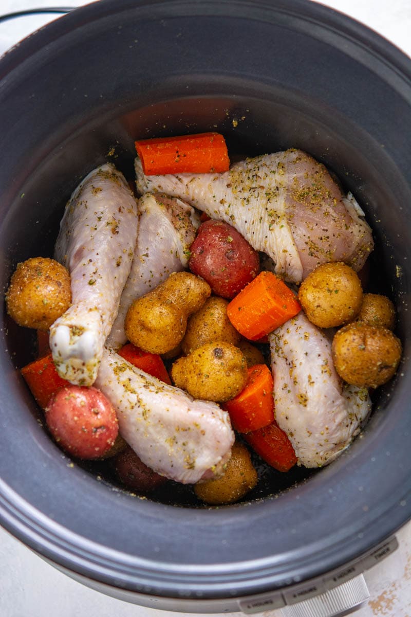 raw chicken, potatoes, and carrots in a slow cooker