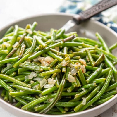 sauteed green beans with garlic in a bowl with fork