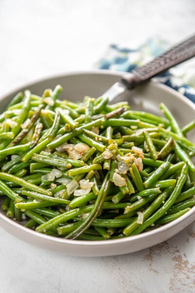 sauteed green beans with garlic in a bowl with fork