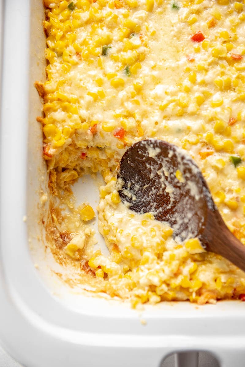 spoon scooping cheesy corn casserole 