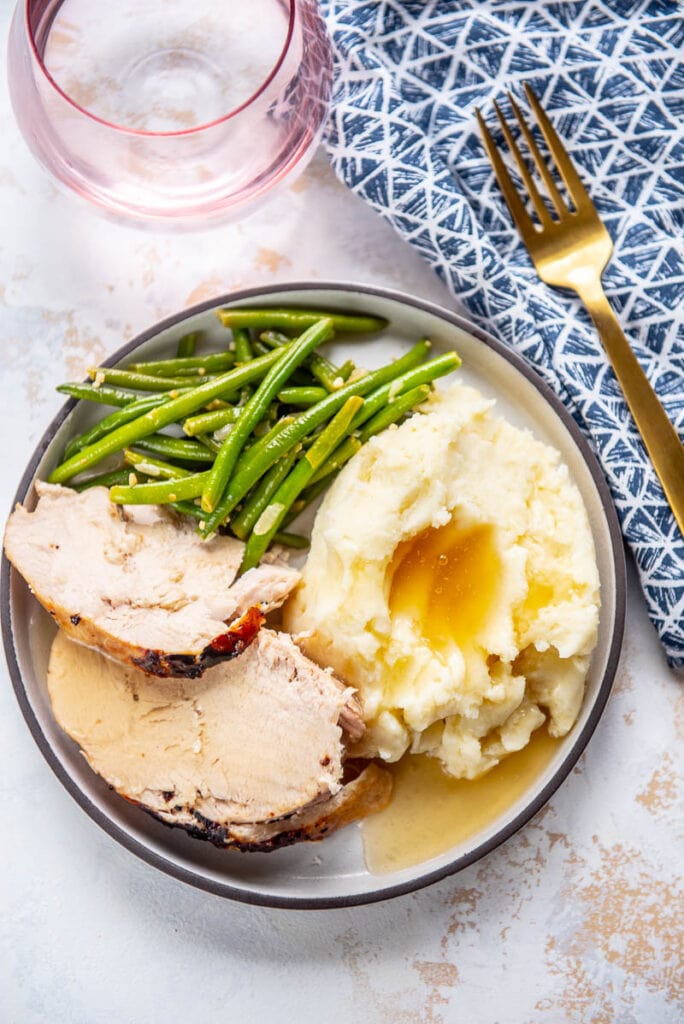 slow cooker turkey breast slices on white plate with sides