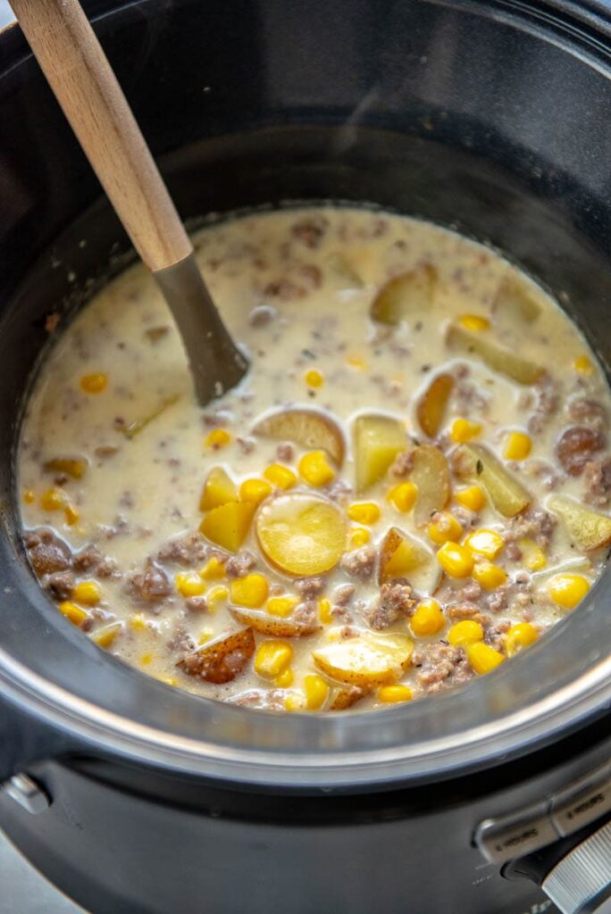 slow cooker with ladle and sausage and potato soup