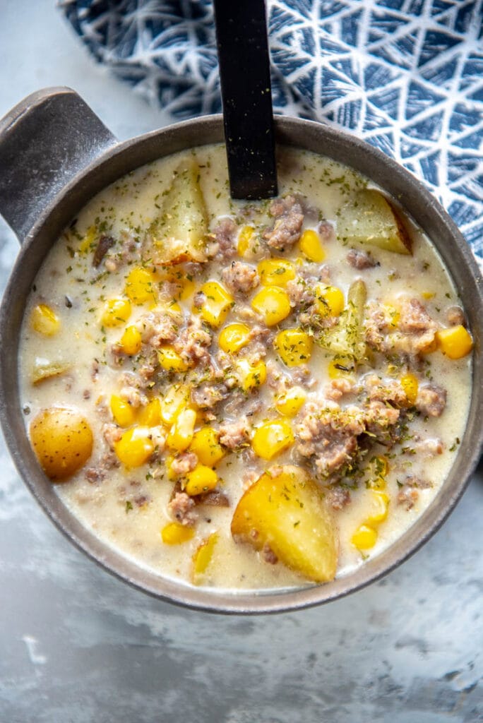 sausage potato and corn soup in gray metal bowl