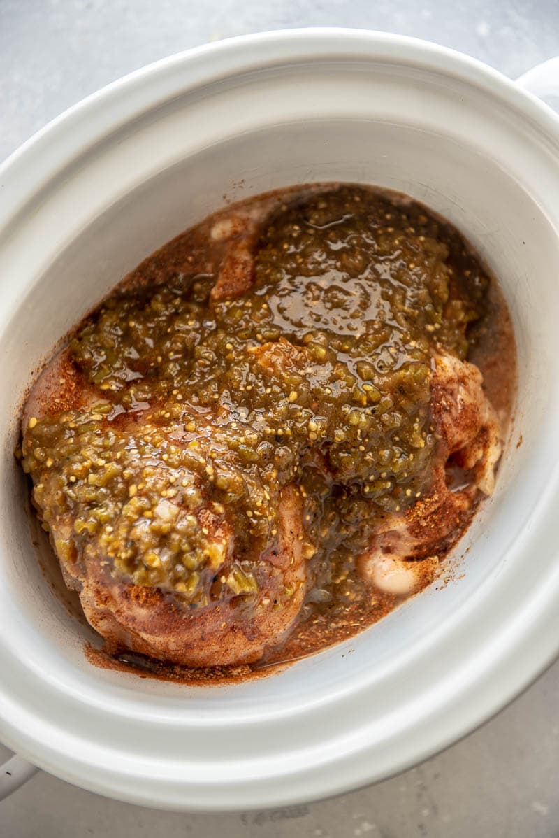 seasoned cooked verde chicken in a slow cooker
