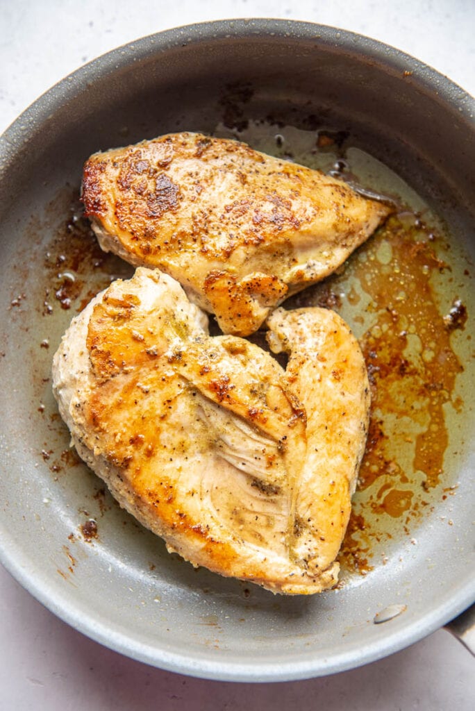 greek chicken and seasonings browning in a pan