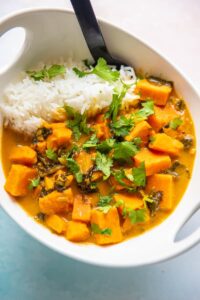 sweet potato curry in a white bowl with spoon