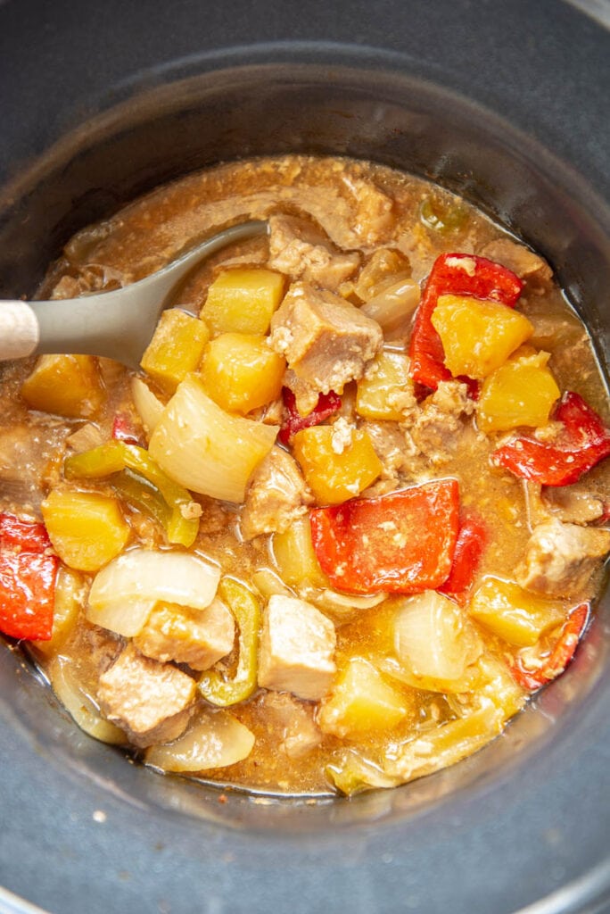 sweet and sour pork in slow cooker with spoon