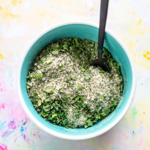 blue bowl filled with seasonings for ranch mix and tiny black spoon