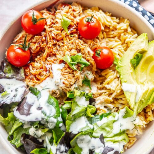 overhead view of bowl filled with lettuce, shredded chicken, avocado and tomatoes