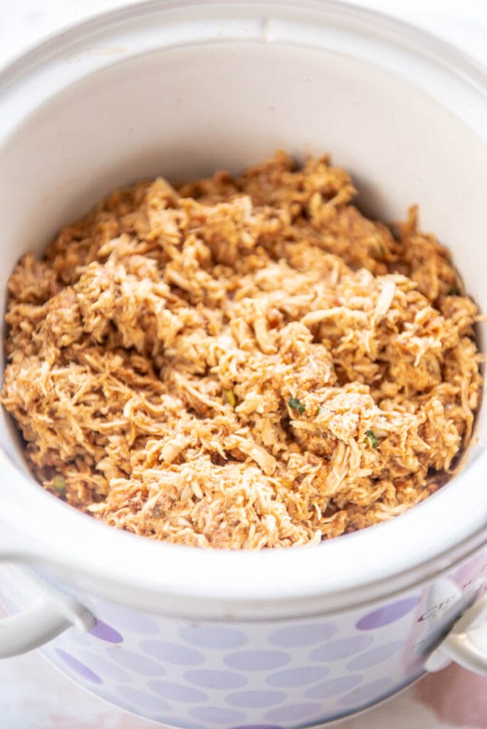 shredded bbq chicken in a round white slow cooker