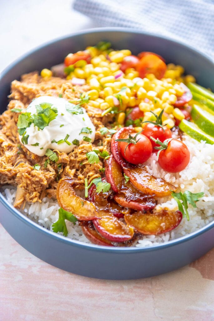 blue bowl filled with chicken, peaches, corn and sour cream