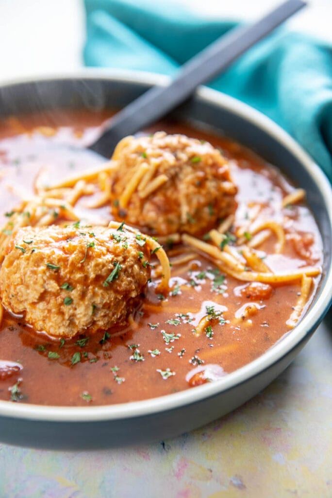 meatballs in spaghetti soup in shallow blue bowl