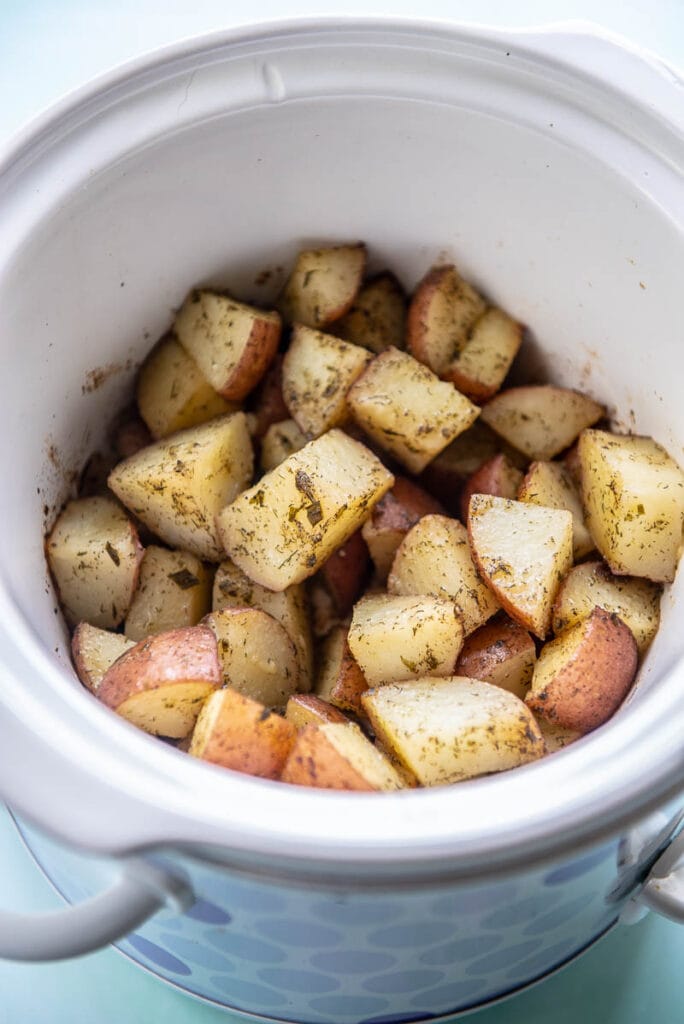 slow cooker filled with cooked red potatoes
