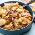blue serving bowl filled with cooked cabbage with bacon