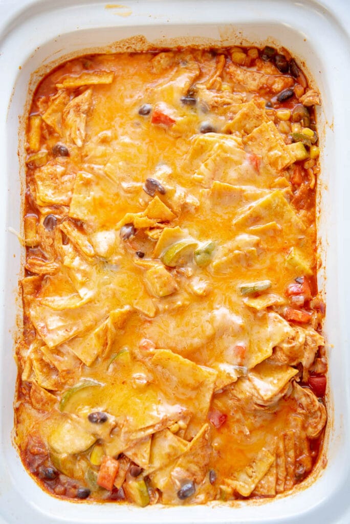 overhead view of enchilada casserole with cheese in a white dish