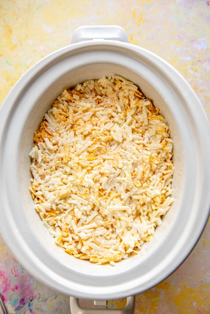white oval slow cooker filled with ready to cook hash brown casserole