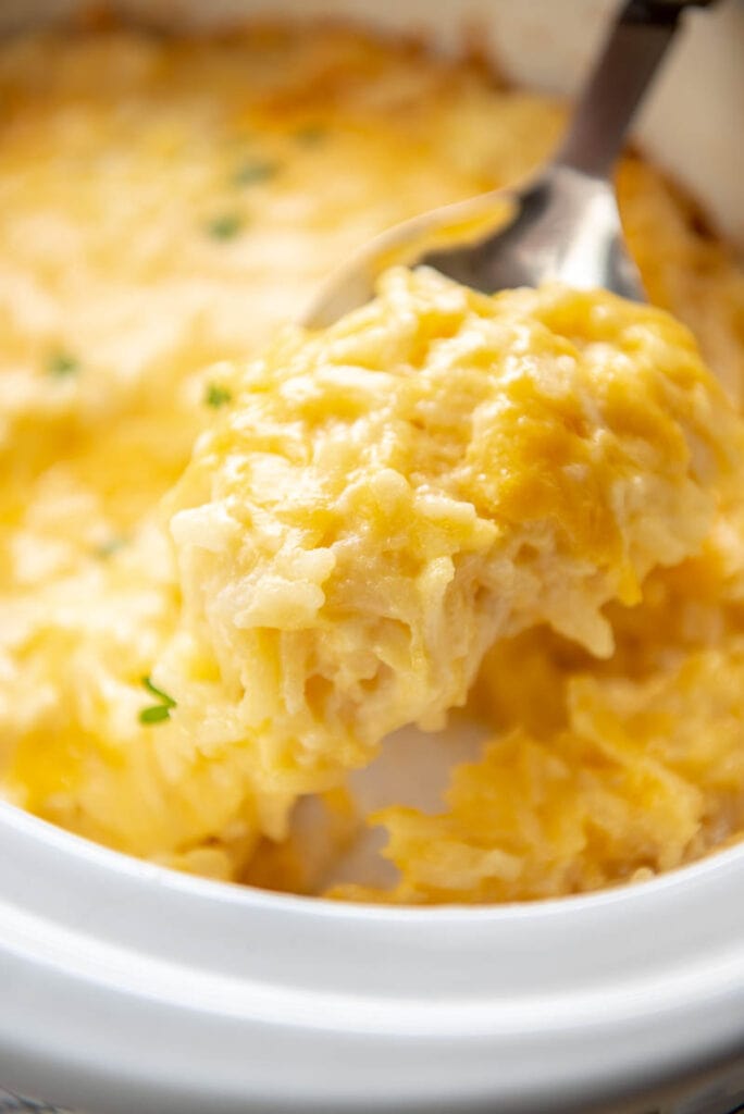 large spoonful of hash brown casserole over slow cooker