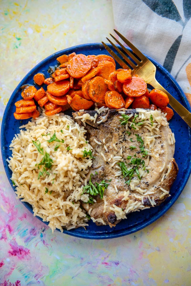 blue plate filled with pork chops, rice and carrots