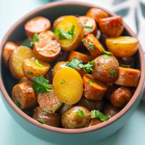 sausage and potatoes in green bowl
