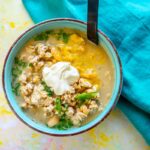 blue bowl filled with white turkey chili topped with sour cream