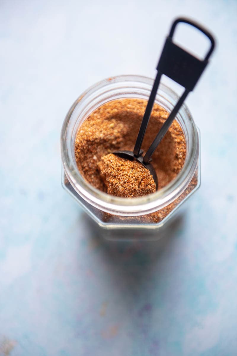 glass jar filled with homemade taco seasoning and a measuring spoon