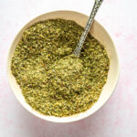 pink bowl with spoon filled with homemade Italian seasoning mix