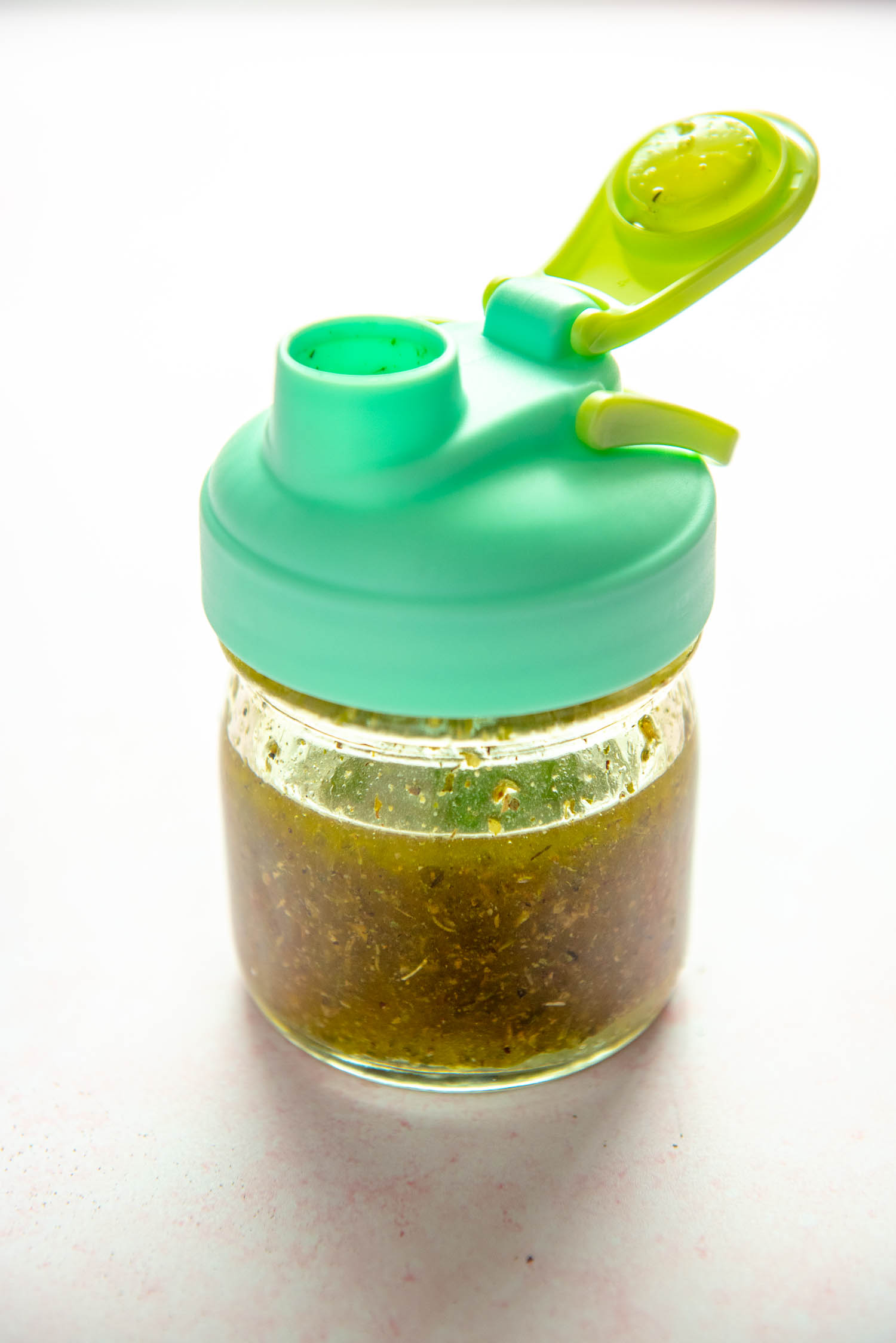 small mason jar with green lid filled with Italian dressing