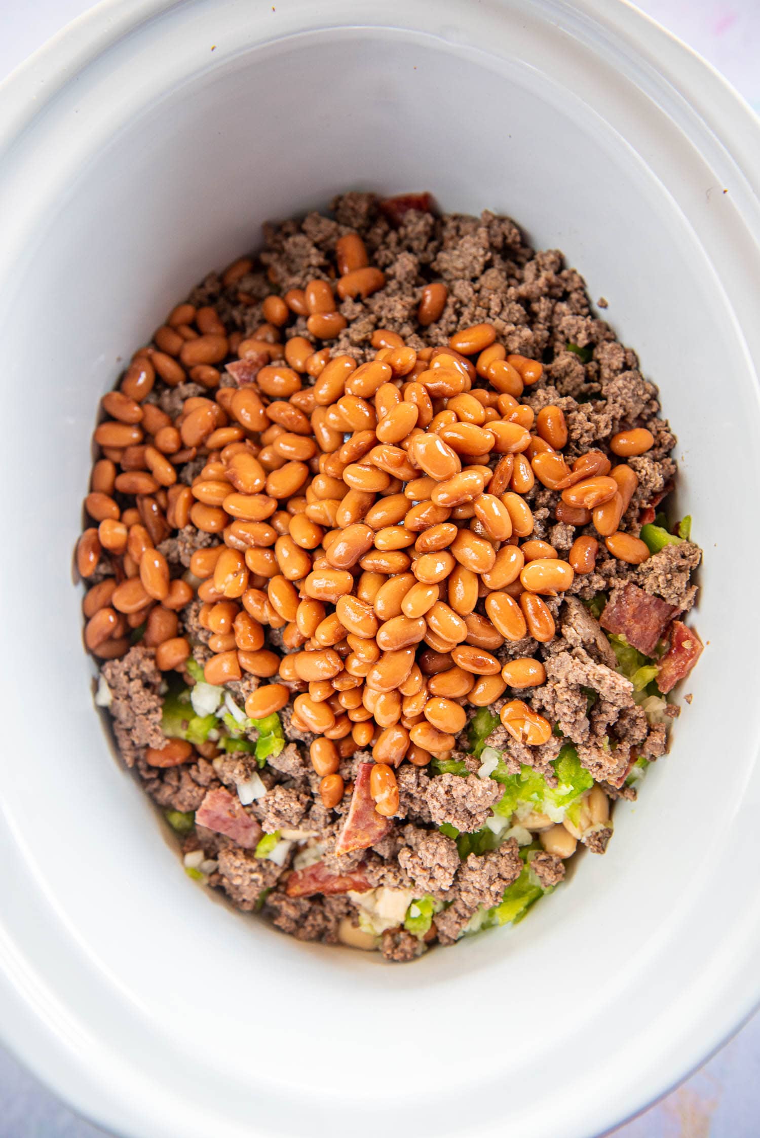 beans over meat and chopped onion and pepper in slow cooker